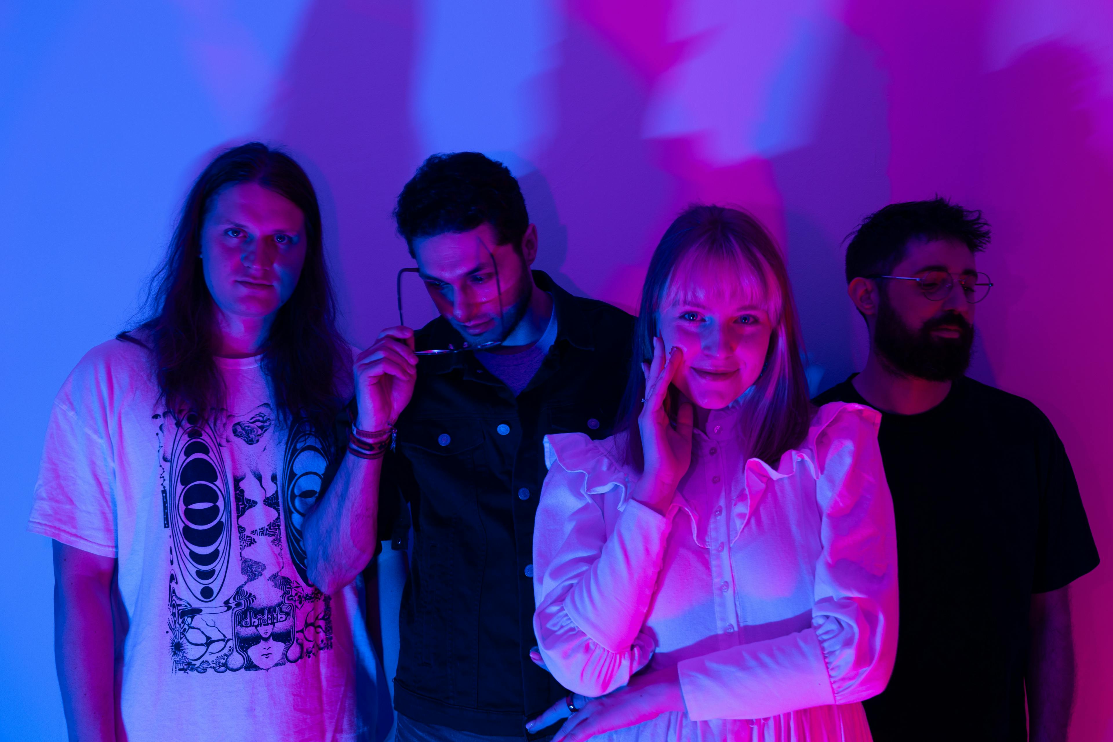 Band members posing under the violet light