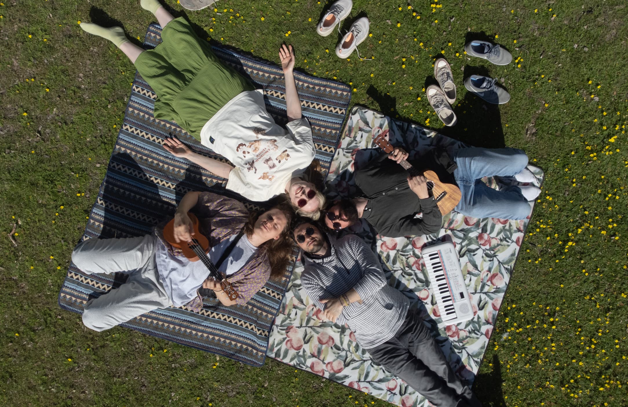 Drone shot of the band members forming a cross while laying on the park